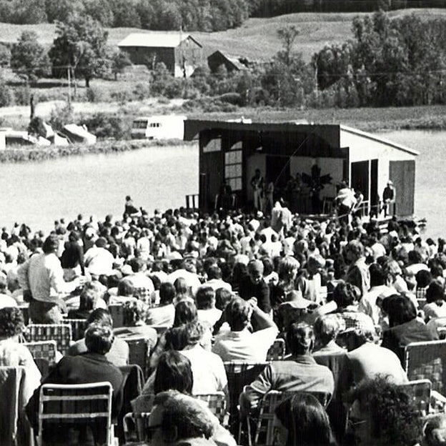 Outdoor event with a stage by a lake, black and white photo